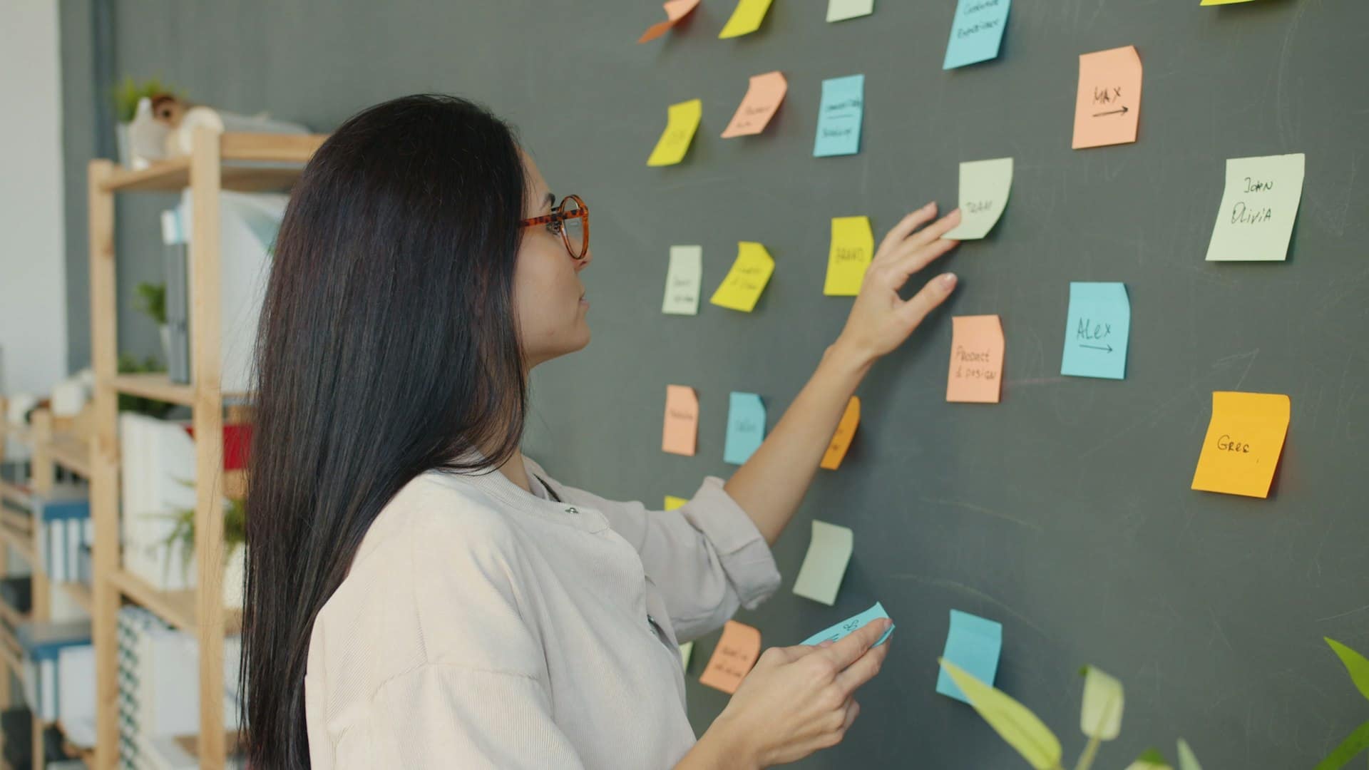A marketer arranging coloured sticky notes on a dark office wall